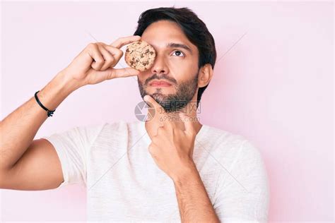西班牙裔帅哥拿着饼干严肃的脸高清图片下载-正版图片503872963-摄图网