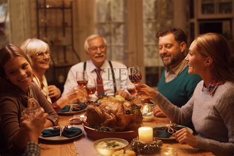 感恩节聚餐时，大家庭在餐厅里互相敬酒。照片摄影图片_ID:429521298-Veer图库