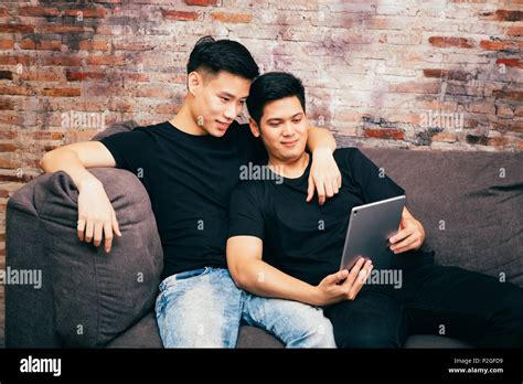 Asian gay couple watching and looking at phone tablet together ...