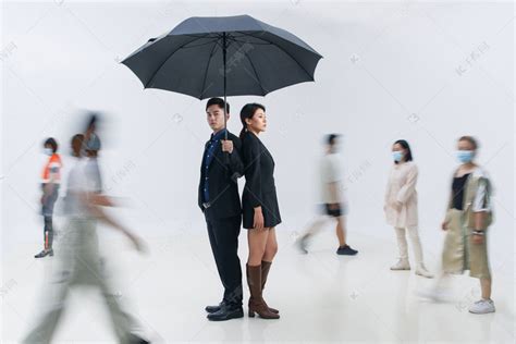 拿着雨伞的商务男女站在人群中高清摄影大图-千库网