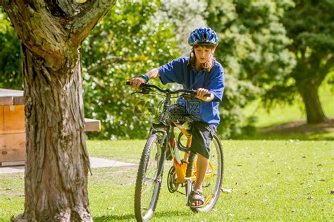 在自然公园背景下骑自行车的快乐青春期前男孩高清图片下载-正版图片507368540-摄图网