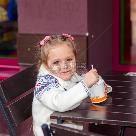 小女孩吃冰淇淋小女孩在街上的咖啡馆里高清图片下载-正版图片507403365-摄图网