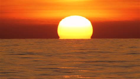 大红热太阳在温暖的空气扭曲上方的海洋地平线，日落在海上，大升起的太阳与云。特写镜头长焦镜头。旅行，开始，自然的概念—高清视频下载、购买_视觉 ...