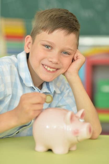 Premium Photo | Young boy putting a coin in a piggy bank