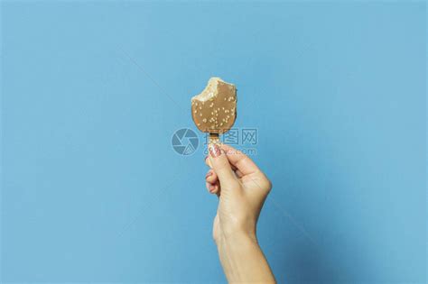 女手握着蓝色背景的一根棍子上被咬的冰淇淋高清图片下载-正版图片506295733-摄图网