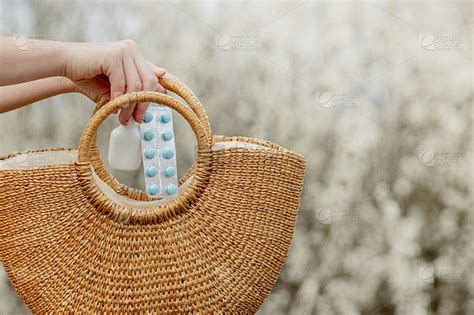 女人的手把过敏药放在袋子里，在开花的背景