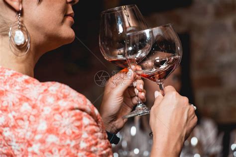 女人拿着一杯酒品酒时桌上有很多不同的酒杯人们会考虑葡萄酒的颜色并尝试在不同的玻璃杯中高清图片下载-正版图片505171419-摄图网