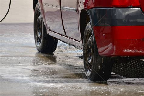 在洗涤过程中的红色汽车在洗车场用泡沫运输在外面的洗车场用加压水手动洗车夏季洗涤使高清图片下载-正版图片506576607-摄图网