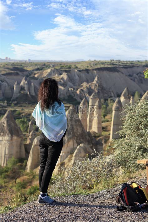 一个年轻的女孩站在悬崖边上，看着地平线、卡帕多奇亚的山谷和蓝天。高清摄影大图-千库网