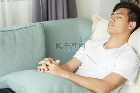 疲惫不堪的懒惰亚洲男子少年在家里的沙发上睡觉休息打盹高清摄影大图-千库网