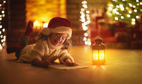 小女孩写信给圣诞老人家附近的圣诞树照片摄影图片_ID:302550474-Veer图库