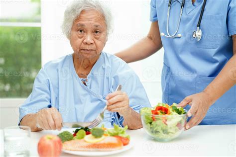 Asian elderly woman patient eating salmon stake and vegetable salad for ...