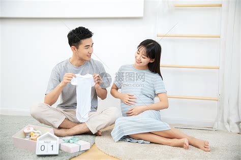 丈夫给孕妇展示自己给孩子买的婴儿衣服高清图片下载-正版图片501369187-摄图网