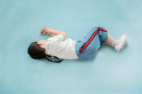 侧躺在蓝色背景上睡觉的小女孩高清摄影大图-千库网