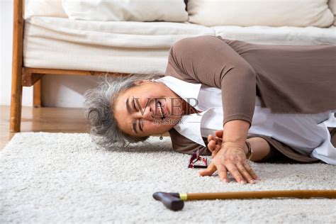 亚洲资深女性跌倒在地毯上，躺在家里客厅的地板上，跌倒的老年人的概念照片摄影图片_ID:377952666-Veer图库