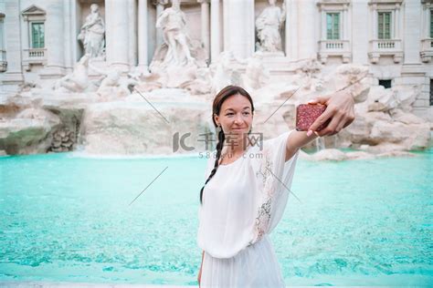 漂亮的女人在意大利罗马旅行期间望着特雷维喷泉。高清摄影大图-千库网