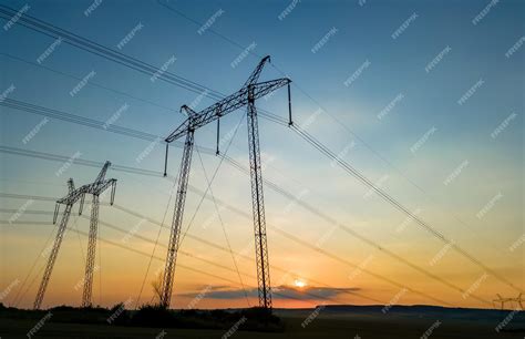 Torres de alta tensión con líneas eléctricas al atardecer | Foto Premium