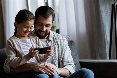 快乐的父亲与女儿拥抱在沙发上抱在家里高清图片下载-正版图片502704950-摄图网