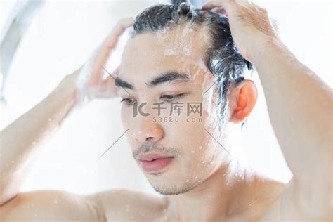 特写年轻人在浴室里用洗发水洗头高清摄影大图-千库网