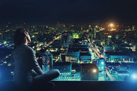 忧郁的女人坐在屋顶上看着夜晚的城市图片下载 - 觅知网