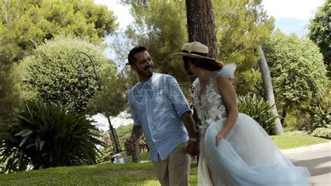 新婚夫妇在夏天在公园跑步行动美丽恩爱的情侣在公园里牵着手浪漫地逃跑白色礼服的妻子牵着她的丈夫的高清图片下载-正版图片504274841-摄图网
