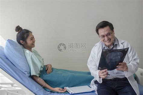 高级男医生一边讲解病人床上的X光片高清图片下载-正版图片506058540-摄图网