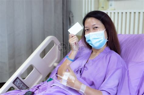 一名专业医生帮助躺在医院病床上的病人，他戴着氧气面罩，正在检查病历高清摄影大图-千库网
