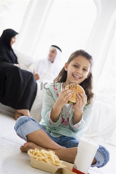 客厅里有快餐的年轻女孩，背景是父母（高调/选择性焦点）高清摄影大图-千库网