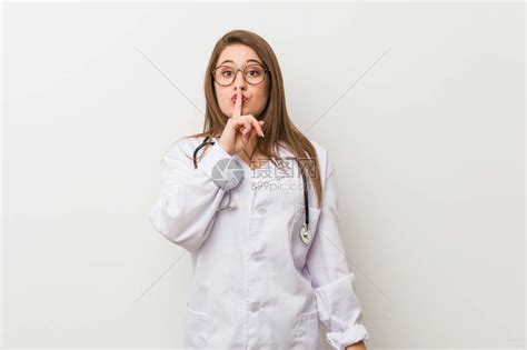 年轻女医生站在白墙上保守秘密或要求保持沉默高清图片下载-正版图片504061026-摄图网