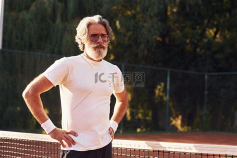 网球场上戴眼镜、白衬衫和黑色运动短裤的高级时尚男士高清摄影大图-千库网
