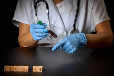 一个带有蓝色手套样本的试管的护士旁边是一个带有covid19字样的木块健康高清图片下载-正版图片506555495-摄图网