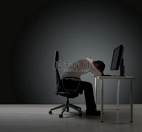 精疲力竭的商人在办公桌上小睡吸顶灯台灯高清摄影大图-千库网