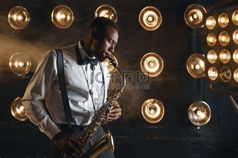 男性爵士乐手在舞台上用聚光灯演奏萨克斯管。吸顶灯卡通动漫人物高清摄影大图-千库网