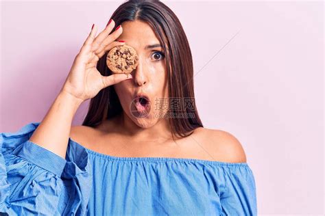 年轻美丽的黑发美女拿着饼干惊吓和惊异张开大口惊讶高清图片下载-正版图片504381865-摄图网