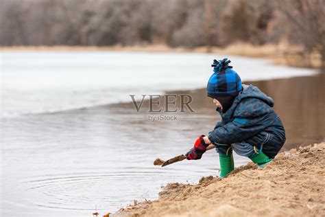 在早春的沙滩上挖沙子的男孩照片摄影图片_ID:354818459-Veer图库