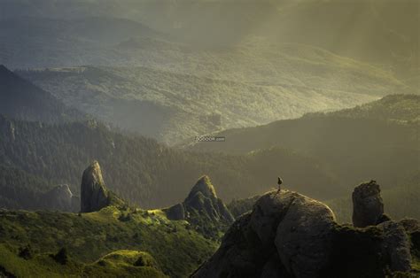 户外运动爱好者站在巨大的岩石上面俯瞰绵延不绝的山峰自然风景素材设计