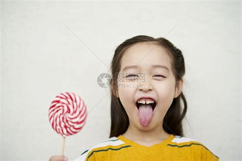 婴儿吃着白色背景上黏黏的棒棒糖。高清摄影大图-千库网