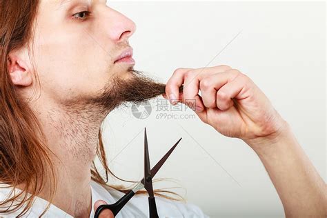 长胡子拿着剪刀的年轻人男孩在下巴上剪头发高清图片下载-正版图片304195100-摄图网