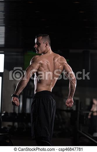 Muscular man flexing muscles in gym. Healthy man standing strong in the ...