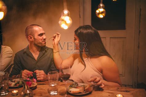 年轻浪漫的女人喂男友在乡村晚餐派对照片摄影图片_ID:304411709-Veer图库