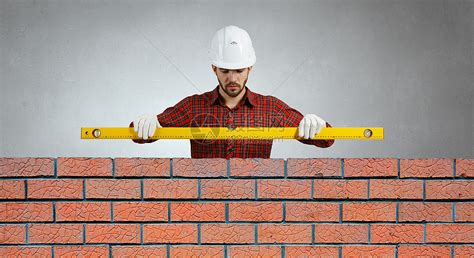 建造者小心地把红砖放在砖石上快速工作的瓦工盖伊测量水平砌体人正在建造砖墙正确计算材料建造者手高清图片下载-正版图片503794841-摄图网
