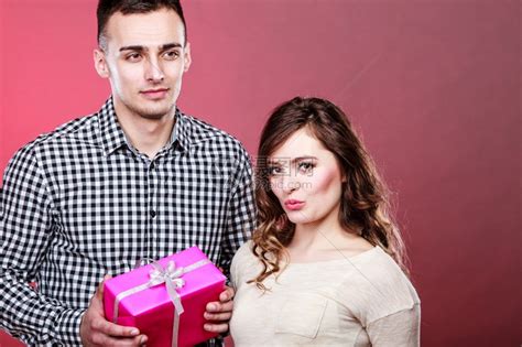 情侣和假日概念英俊的年轻男子令人惊讶的可爱女红背景粉色礼物盒高清图片下载-正版图片306471984-摄图网