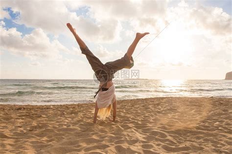享受阳光自由和生活的轻松女人在日落时在美丽的海滩上转动车轮年轻的女士感到自由放松和快乐假期自由幸福高清图片下载-正版图片503515680-摄图网
