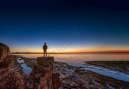 男人站在悬崖上俯瞰大海夕阳逆光剪影高清图片下载-正版图片600021649-摄图网
