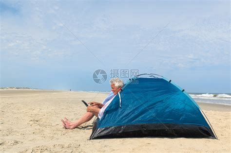 单身老人在海滩的避难所内有数字石板露营药片荷兰互联网高清图片下载-正版图片307808712-摄图网