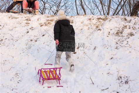 一个女孩带着雪橇跑上山高清摄影大图-千库网
