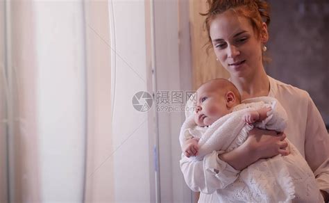 妈怀里抱着一个刚出生的婴儿女孩在窗前抱着一个婴儿母亲高清图片下载-正版图片505468429-摄图网