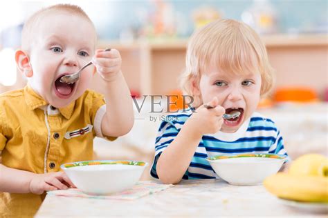 幼儿园里用盘子吃东西的有趣小孩照片摄影图片_ID:124397808-Veer图库