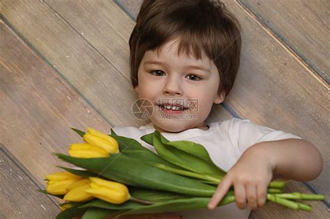 一个拿着一束黄色郁金香的小孩一个男孩拿着花瓶里的鲜花礼物女假期女孩的礼物高清图片下载-正版图片505459996-摄图网