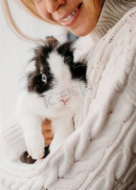 兔子一个穿着白色针织毛衣的女孩抱着一只灰色的兔子并在镜头前与他合影一个女孩在街上和一只灰兔子玩耍与动物高清图片下载-正版图片505172637-摄图网